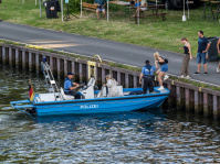 Ein Polizei-Boot auf dem Wasser hält am Ufer an.
