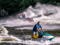 Zwei Jetski-Fahrer erzeugen auf dem Wasser sprühende Tropfen und Wellen.