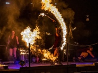 Eine Frau vollführt eine Feuershow mit brennenden Stäben in der Nacht.