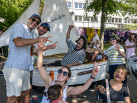 Ein Mann im Piratenkostüm sitzt in einem kleinen Boot an Land, um ihn herum sind Personen, die jubeln.