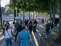Viele Menschen gehen auf einem Weg am Flussufer.