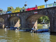 Drei Drachenboote stehen auf dem Wasser unter einer Brücke.
